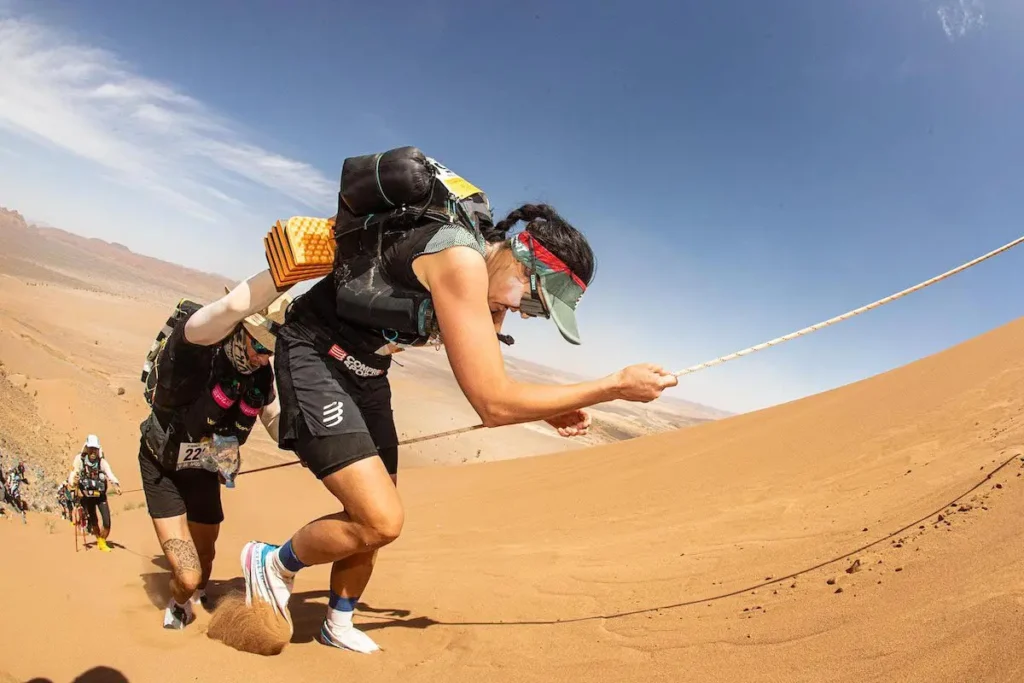 Endurance runner training in desert heat with backpack for Marathon des Sables preparation