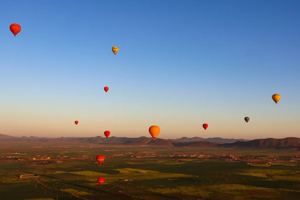 Aerial view from a hot air balloon in Marrakech showing terracotta land and snow-capped Atlas Mountains