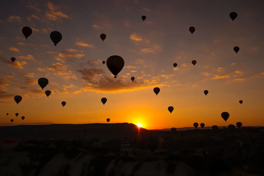 Silhouette of a traveler photographing the sunrise during a hot air balloon in Marrakech flight